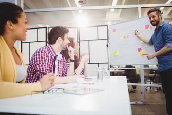 Happy young male executive explaining colleagues at creative office